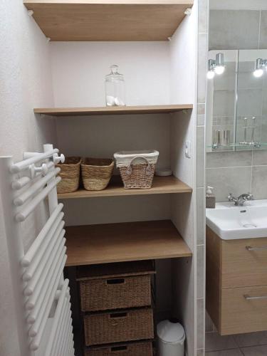 une salle de bain avec un lavabo et une étagère avec des paniers dans l'établissement Petit appartement aux Stes Maries de la Mer, à Saintes-Maries-de-la-Mer