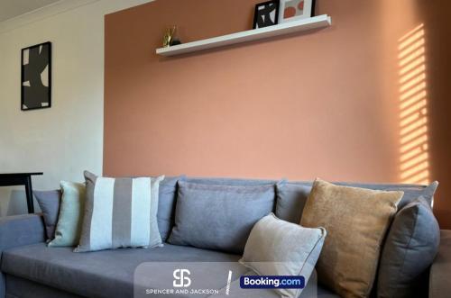 a blue couch with pillows in a living room at 2 Bedroom Spacious Duplex with Free Parking Near The University - By Spencer & Jackson Short Lets & Serviced Accommodation Oxford in Oxford