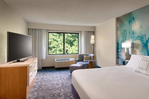 a hotel room with a bed and a flat screen tv at Courtyard by Marriott Charlotte Airport LoSo in Charlotte
