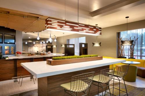 a kitchen with a bar with chairs and a table at Courtyard by Marriott Charlotte Airport LoSo in Charlotte
