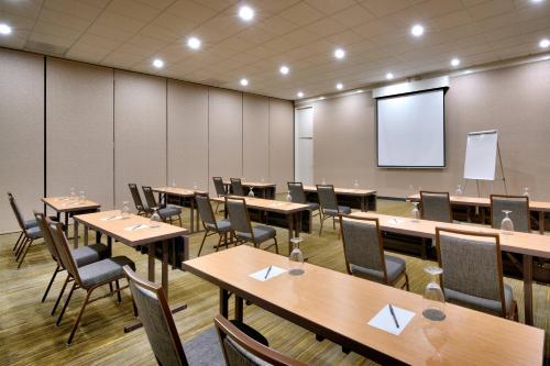 a conference room with tables and chairs and a screen at Courtyard by Marriott Charlotte Airport LoSo in Charlotte