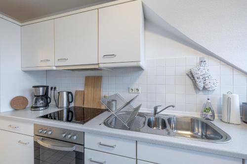 a kitchen with white cabinets and a sink at Apartment in Uni- und Citynähe in Oldenburg