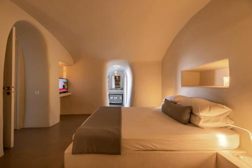 a bedroom with a large bed with an arched window at 270 Oias View in Oia