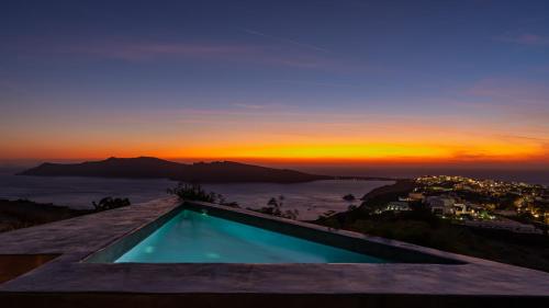 a swimming pool on top of a house with a sunset at 270 Oias View in Oia