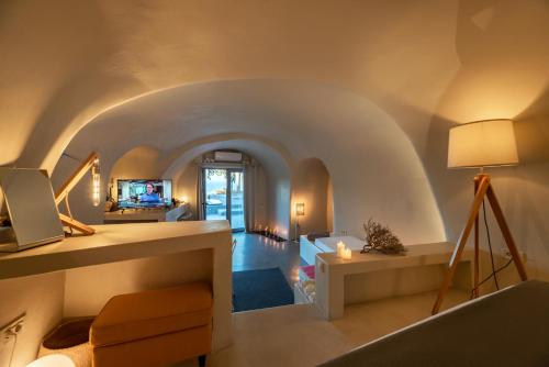 a living room with an archway with a couch and a tv at 270 Oias View in Oia
