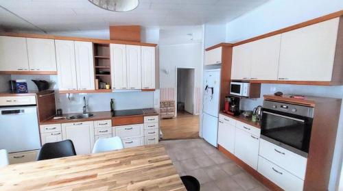 a large kitchen with white cabinets and a wooden table at Tilava ja tunnelmallinen 26m2 huone max kuudelle hengelle in Kerava