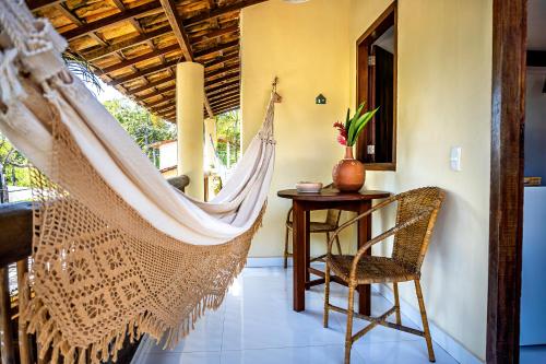 a hammock in a room with a table and a chair at Pousada Campestre in Trancoso