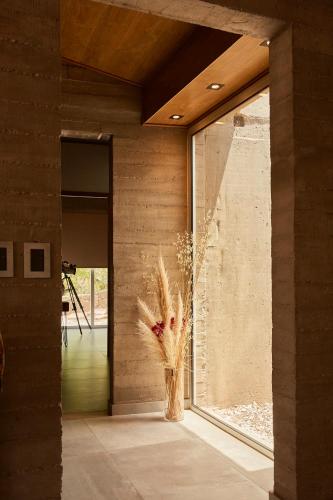 a vase with flowers in a room with a window at La Quebrada Potrerillos - Lodges de Montaña in Potrerillos