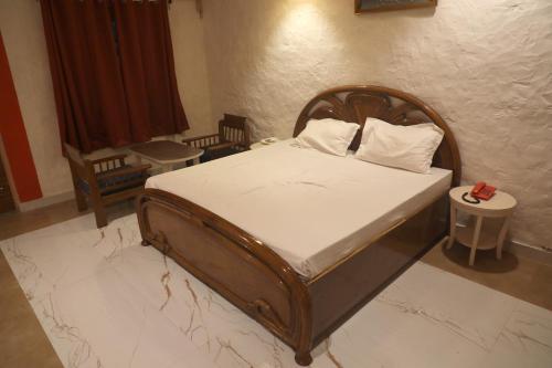 a bedroom with a wooden bed with white sheets at Wow Relish in Alwar