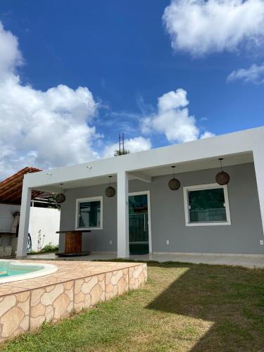 a white house with a swimming pool in front of it at Casa Arembepe in Camaçari