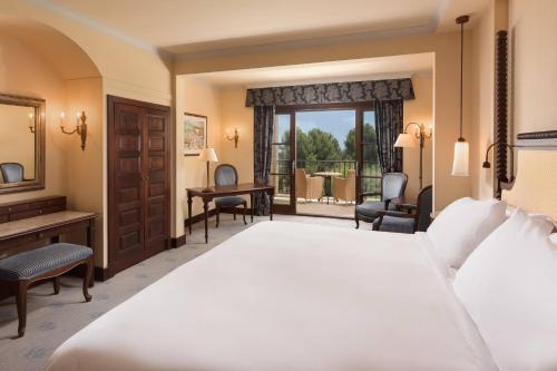 a bedroom with a large white bed and a desk at Castillo Hotel Son Vida, a Luxury Collection Hotel, Mallorca in Palma de Mallorca