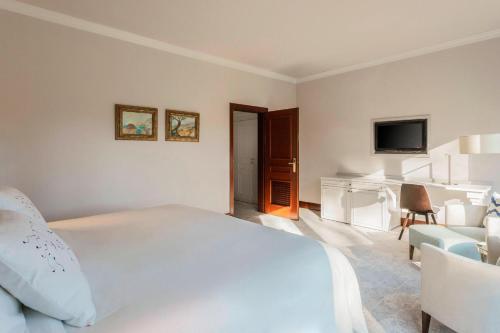 a bedroom with a white bed and a living room at Castillo Hotel Son Vida, a Luxury Collection Hotel, Mallorca in Palma de Mallorca