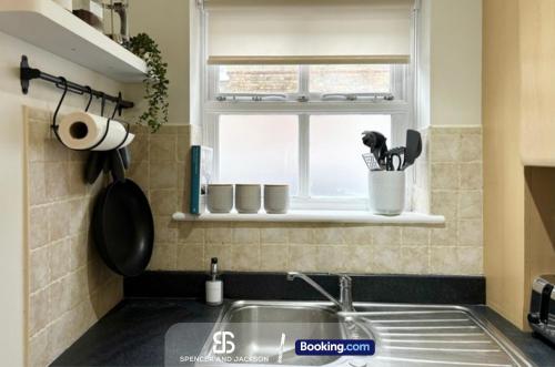 a kitchen with a sink and a window with cups at 3 Bedroom Stylish Oxford Townhouse Near The University By Spencer And Jackson Short Lets & Serviced Accommodation in Oxford