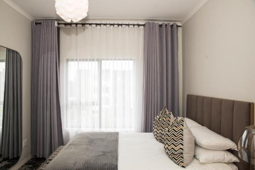 a bedroom with a bed with a large window at Eirini Elegant - Hermes Apartment in Midrand