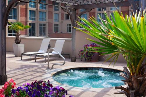 a hot tub on a patio with chairs and flowers at Houston Marriott Sugar Land in Sugar Land