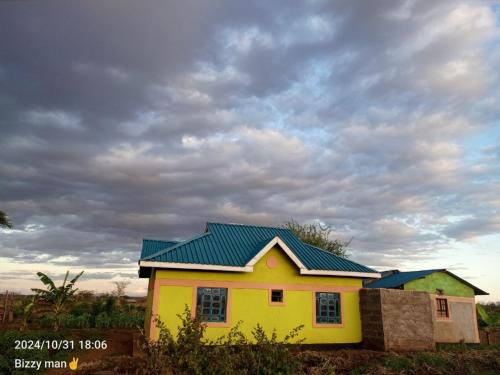 a yellow and green house with a cloudy sky at Sammyvero farm in Chala