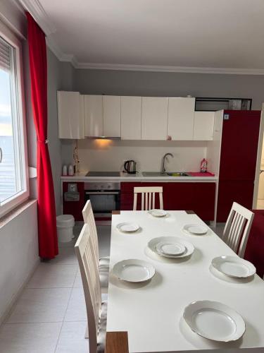 a kitchen with a white table with chairs and a kitchen with white cabinets at Deluxe Apartments Shengjin in Shëngjin