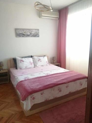 Sandra's apartment في بيتولا: غرفة نوم بها سرير بملاءات وردية ونافذة
