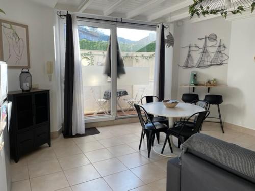 un salon avec une table et des chaises et une fenêtre dans l'établissement Côté Baie avec parking wifi draps et serviettes, à Hendaye