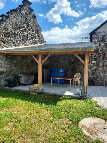 a pavilion with a picnic table and a stone wall at Maison de village au pied des Pyrénées in Marignac