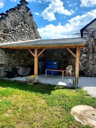 a pavilion with a picnic table and a stone wall at Maison de village au pied des Pyrénées in Marignac
