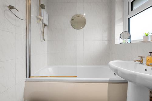 a white bathroom with a tub and a sink at Stylish 3-Bed Close to MCR City Centre for 8 Guests in Manchester