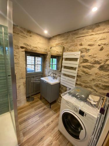 une salle de bain avec une machine à laver et un lavabo dans l'établissement La maison Colombe, à Molinot