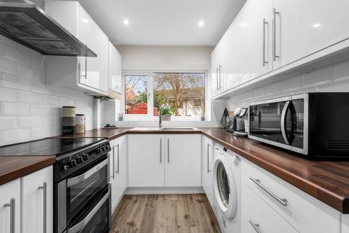 a kitchen with white cabinets and a microwave oven at Stylish 3-Bed Close to MCR City Centre for 8 Guests in Manchester