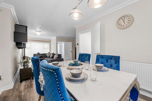 a dining room with a white table and blue chairs at Stylish 3-Bed Close to MCR City Centre for 8 Guests in Manchester