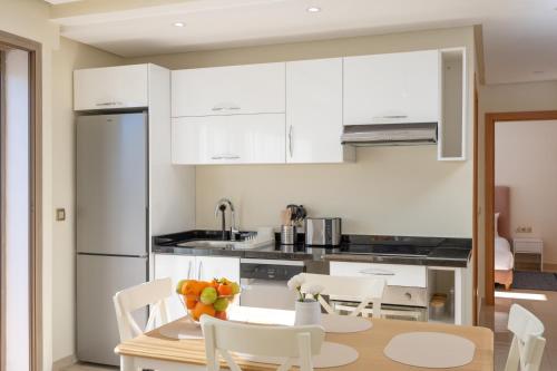 a kitchen with white cabinets and a table and chairs at Charming Cozy apartments with terrace, Haut Agdal in Rabat