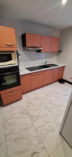 an empty kitchen with orange cabinets and a sink at S-e-r-a-l-y 1 in Égliseneuve-dʼEntraigues