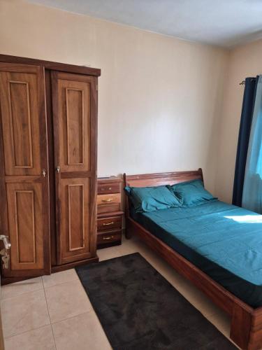 una camera da letto con un letto e un armadio in legno di Appartement Caraïbe a Rufisque