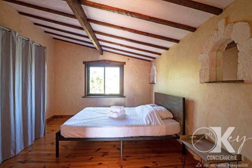 une chambre avec un lit dans une pièce avec une fenêtre dans l'établissement Maison familiale de charme avec piscine 6-8 personnes, à Laurens