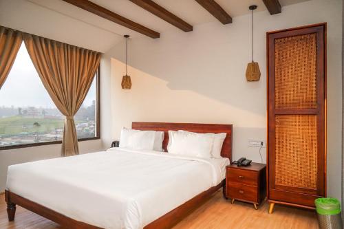 a bedroom with a large white bed and a window at Virgin Valley Leisure Resort in Ooty