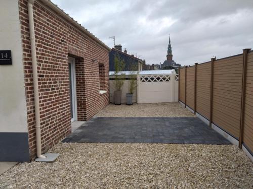 a driveway with a white gate and a brick fence at Maison individuelle centre ville "TIMAJO" in Bapaume
