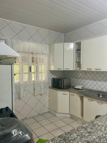 a kitchen with white cabinets and a shower at Casa Vista Pedra Azul in Domingos Martins