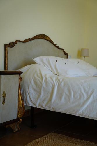 Una cama con sábanas blancas y un cabecero de madera. en Rustic charm, Olivo Suite with private bathroom and unique views, en Alzira