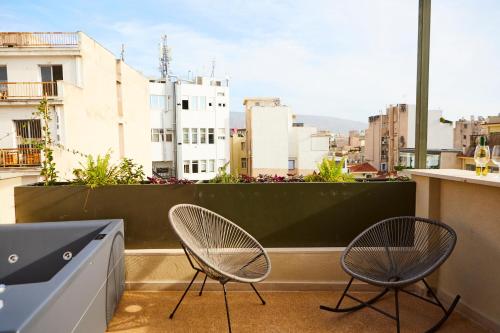 two chairs on a balcony with a view of a city at Mosaics Athens Boutique Apartments in Athens