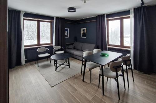 Una sala de estar con una mesa y sillas y un sofá. en Nova Planina Jahorina, en Jahorina