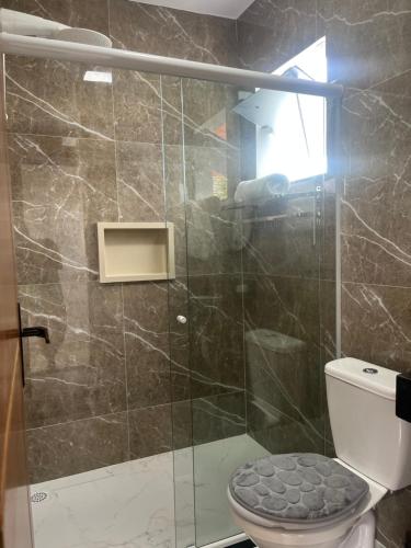 a bathroom with a glass shower with a toilet at Suitella in Cabo Frio