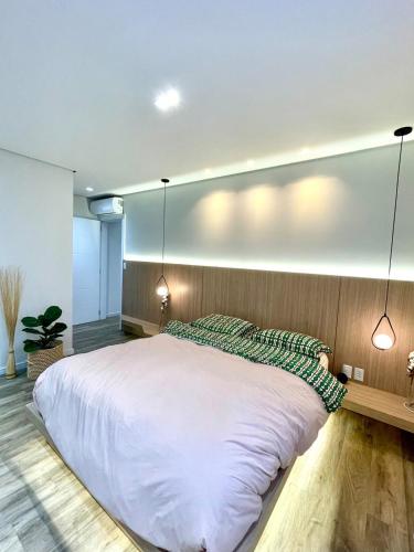 a bedroom with a large white bed and two lights at Cobertura Amanhecer em Dois Irmãos in Dois Irmãos