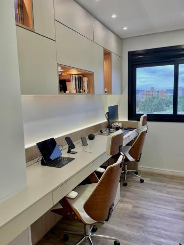 an office with a long desk with chairs and a laptop at Cobertura Amanhecer em Dois Irmãos in Dois Irmãos