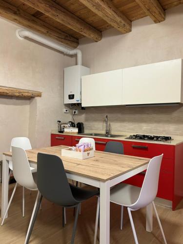 a kitchen with a wooden table and white chairs at Larocca Tourist Home 1 Valbrenta in Carpane