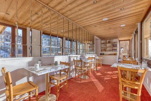 a restaurant with wooden ceilings and tables and chairs at Hôtel Lyret in Chamonix-Mont-Blanc