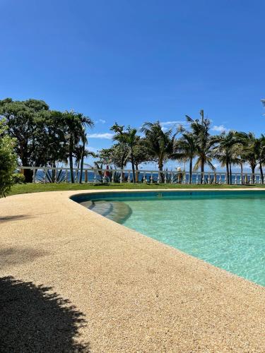 a swimming pool with palm trees in the background at Gold View Beachfront Resort in Timbaon