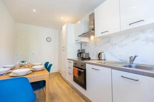 une cuisine avec des armoires blanches et une table en bois dans l'établissement T5 Idéal Groupes & Familles, St Charles-Joliette, à Marseille