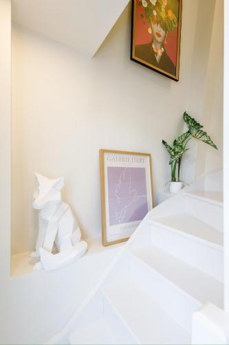 une chambre blanche avec une photo et une plante dans l'établissement Lovely Duplex, à Trouville-sur-Mer