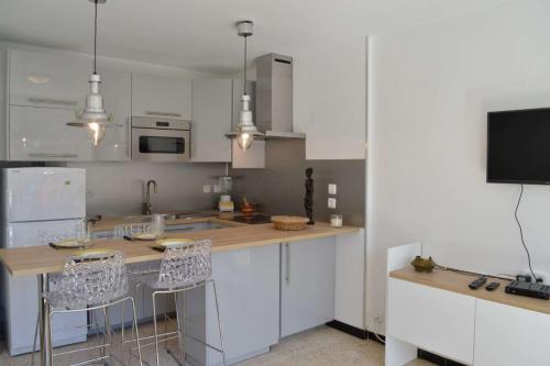 une cuisine avec des armoires blanches et une table avec des chaises dans l'établissement SP920-002 Appartement 2 pièces SAINT PIERRE LA MER, à Saint Pierre La Mer