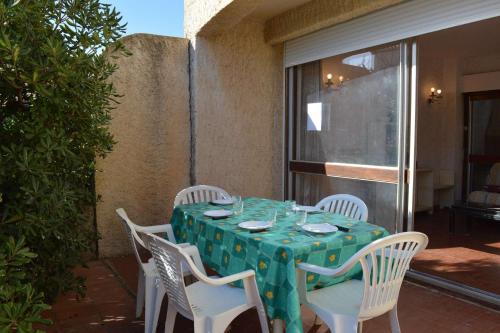 une table avec des chaises blanches et un tissu de table vert dans l'établissement SP620-033 Maison 4 pièces SAINT PIERRE LA MER, à Saint Pierre La Mer