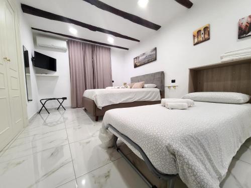 two beds in a room with white walls at la casa di patta a spaccanapoli in Naples